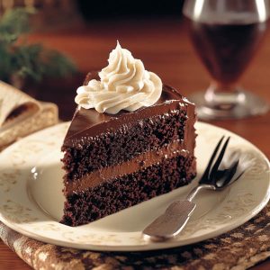 Rich frosted fudge cake with layers of moist chocolate sponge, creamy fudge frosting, and a glossy finish.