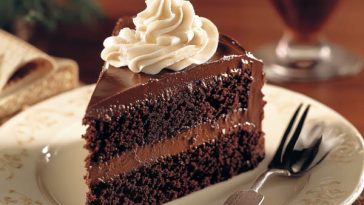 Rich frosted fudge cake with layers of moist chocolate sponge, creamy fudge frosting, and a glossy finish.