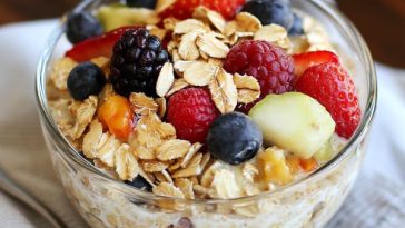 A mason jar filled with creamy overnight oats topped with fresh berries, chia seeds, and a drizzle of honey.