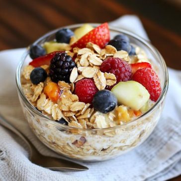 A mason jar filled with creamy overnight oats topped with fresh berries, chia seeds, and a drizzle of honey.