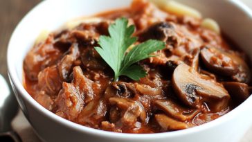 "A bowl of slow cooker beef and mushroom ragù served over pasta, garnished with fresh parsley and parmesan."