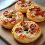 Toasted bagels topped with marinara sauce, melted mozzarella cheese, and pepperoni slices, served warm on a tray.