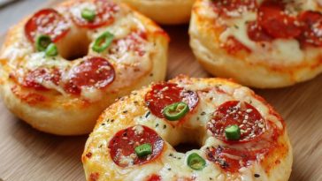 Toasted bagels topped with marinara sauce, melted mozzarella cheese, and pepperoni slices, served warm on a tray.