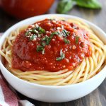 Homemade marinara sauce simmering in a pot with tomatoes, garlic, onions, and fresh basil.