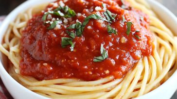 Homemade marinara sauce simmering in a pot with tomatoes, garlic, onions, and fresh basil.