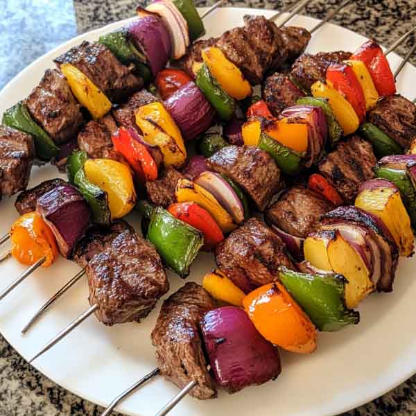 Juicy steak kebabs grilled with colorful bell peppers, onions, and zucchini, brushed with savory marinade.