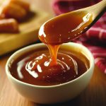 Golden microwave caramel sauce in a glass jar, drizzled over ice cream with a spoon beside it.