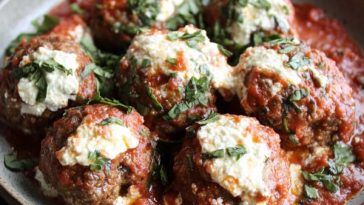 Slow cooker ricotta stuffed meatballs simmered in marinara sauce, garnished with fresh basil and parmesan.