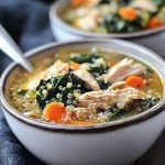 Slow cooker quinoa, chicken, and kale soup served in a rustic bowl, garnished with fresh herbs.