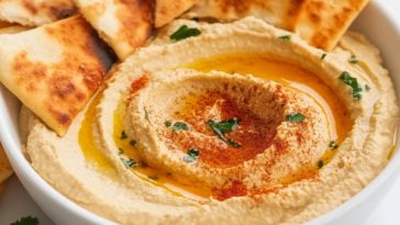 Creamy homemade hummus served with golden baked pita chips, garnished with olive oil and paprika.