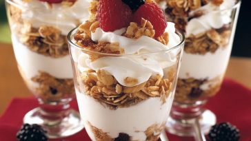 Layered yogurt parfaits in glass jars with granola, berries, and a drizzle of honey.