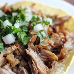 Juicy pork carnitas cooked until tender, then crisped to perfection, served with tortillas, lime, and fresh toppings.