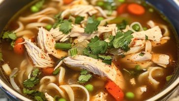 "A steaming bowl of peppery chicken noodle soup with tender chicken, fresh vegetables, and noodles in a savory broth."
