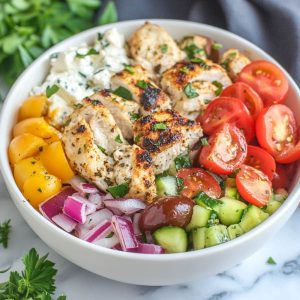 Greek chicken bowls with marinated grilled chicken, fresh cucumber, tomato, olives, feta, and tzatziki sauce served over rice.