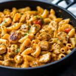 One pot Cajun chicken pasta with creamy sauce, tender chicken, penne pasta, and colorful bell peppers served in a skillet.