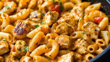 One pot Cajun chicken pasta with creamy sauce, tender chicken, penne pasta, and colorful bell peppers served in a skillet.