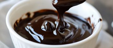 Rich homemade hot fudge sauce poured over vanilla ice cream, topped with whipped cream and chocolate shavings.