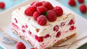Raspberry icebox cake layered with graham crackers, whipped cream, and fresh raspberries, chilled until set and served cold.