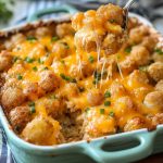 Golden baked tater tot casserole layered with ground beef, creamy sauce, melted cheese, and crispy tater tots on top.