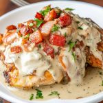 Juicy chicken breasts smothered in melted cheese, crispy bacon, fresh tomatoes, and lettuce, served on a rustic plate.