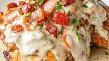 Juicy chicken breasts smothered in melted cheese, crispy bacon, fresh tomatoes, and lettuce, served on a rustic plate.