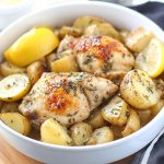 Greek slow cooker lemon chicken with golden potatoes, garnished with herbs and lemon slices in a rustic serving dish.