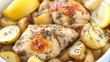 Greek slow cooker lemon chicken with golden potatoes, garnished with herbs and lemon slices in a rustic serving dish.