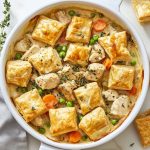 Chicken pot pie with puff pastry bites filled with creamy chicken, vegetables, and golden flaky pastry topping served in a casserole dish.