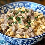 Crock Pot beef stroganoff with tender beef, mushrooms, and creamy sauce served over egg noodles.