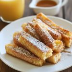Golden baked French toast sticks coated in cinnamon sugar, served with maple syrup for dipping.