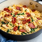 One pot chicken risoni topped with crispy salami slices in a rustic pan