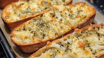 Homemade garlic bread with melted cheese and herbs on a wooden board