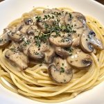 Plate of spaghetti topped with creamy mushroom herb sauce and fresh parsley