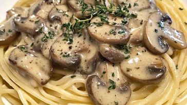 Plate of spaghetti topped with creamy mushroom herb sauce and fresh parsley