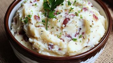 Bowl of creamy garlic ranch mashed potatoes garnished with fresh herbs.