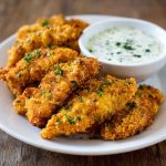 Crispy chicken tenders served with a bowl of Greek yogurt ranch dip.