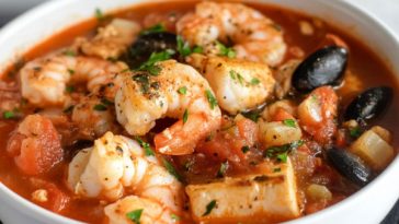 Bowl of cioppino seafood stew with shrimp, mussels, clams, and fish in tomato broth.