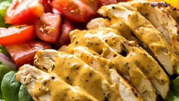 Bowl of honey mustard chicken salad with fresh greens, grilled chicken, and drizzled dressing.