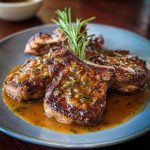 Seared lamb chops with rosemary gravy on a plate with mashed potatoes