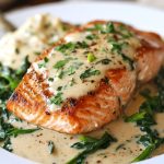 Pan-seared salmon fillets topped with creamy garlic sauce, garnished with fresh herbs.