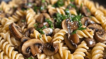 Mushroom pasta garnished with fresh herbs in a bowl