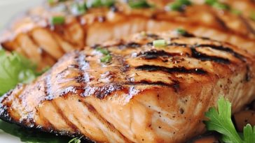 Grilled salmon fillet with herbs and lemon slices on a plate