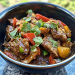 Xinjiang cumin lamb stir fry with sliced lamb, cumin spices, red chilies, and onions in a wok.