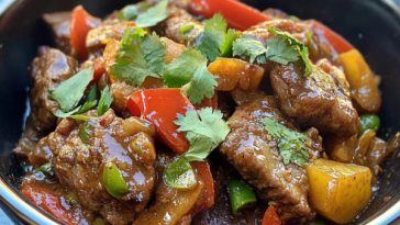 Xinjiang cumin lamb stir fry with sliced lamb, cumin spices, red chilies, and onions in a wok.