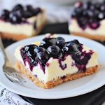 Blueberry cheesecake bars with swirled blueberry topping on a plate