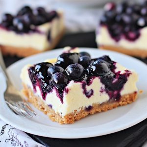 Blueberry cheesecake bars with swirled blueberry topping on a plate