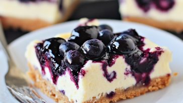 Blueberry cheesecake bars with swirled blueberry topping on a plate