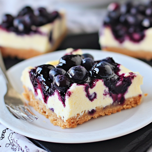 Blueberry cheesecake bars with swirled blueberry topping on a plate