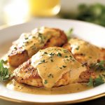 Chicken breasts in creamy mustard sauce garnished with parsley in a skillet