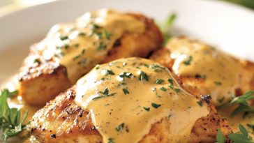Chicken breasts in creamy mustard sauce garnished with parsley in a skillet